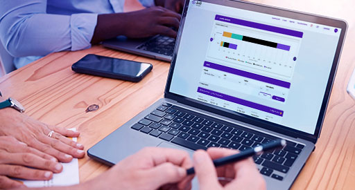 Two colleagues reviewing a clinical trial process data dashboard on a laptop.